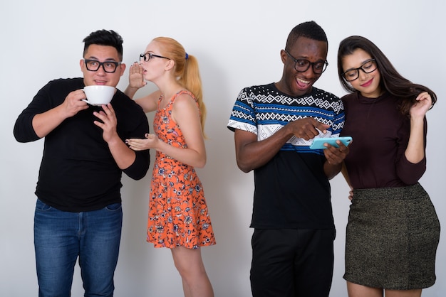 Felice gruppo eterogeneo di amici multietnici smilingng durante l'utilizzo dei telefoni