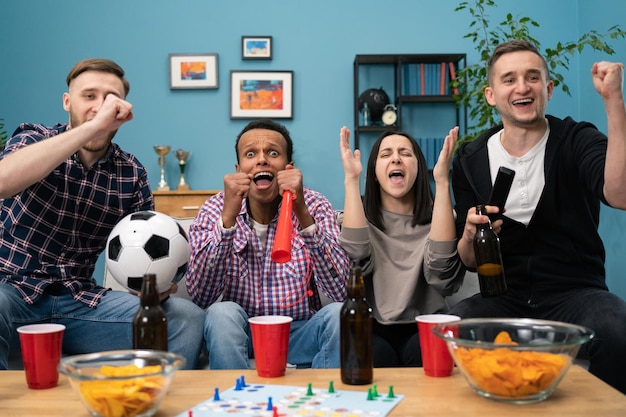 Happy diverse group of student sports fans throwing arms up in excitement celebrating goal watching