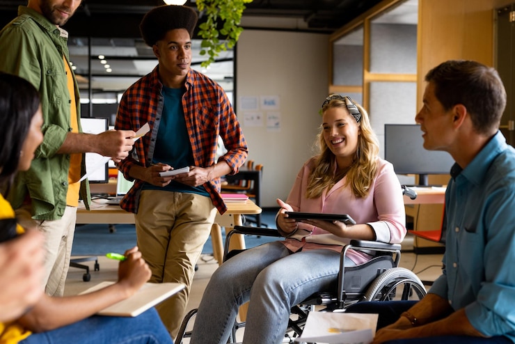 Photo happy diverse male and female colleagues in discussion using tablet in casual office meeting. casual office, teamwork, disability, inclusivity, business and work, unaltered.