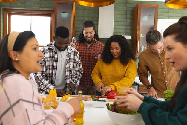 Photo happy diverse male and female friends preparing meal and drinking drinks in kitchen