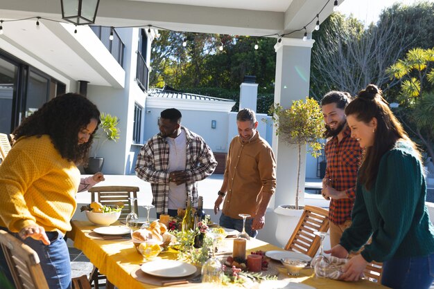 Photo happy diverse male and female friends serving thanksgiving celebration meal in sunny garden