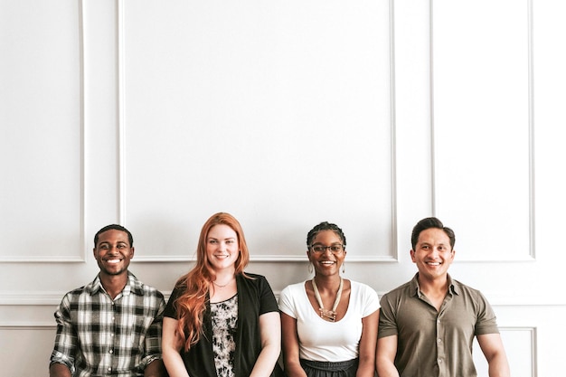 Happy diverse people sitting by a white wall