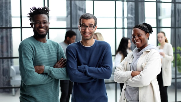 Photo happy diverse professional business team in casual wear standing in the office and looking at the camera smiling