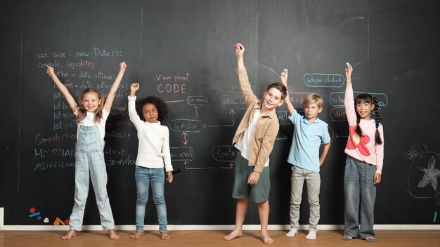 Photo happy diverse student raising hands up while standing at blackboard erudition