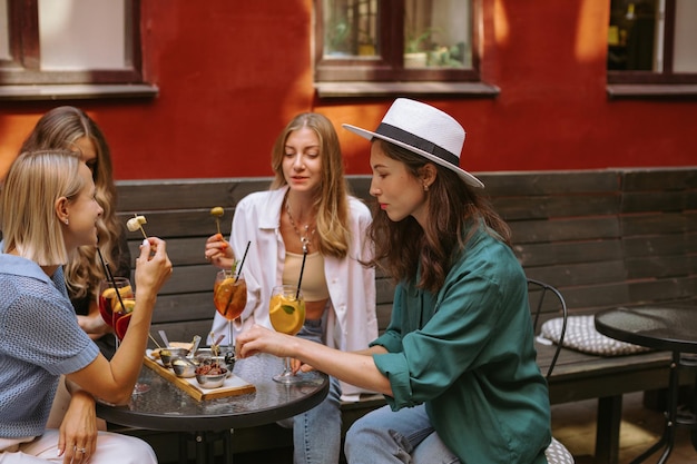 Фото Счастливые разнообразные женщины с напитками отдыхают в летнем кафе вместе
