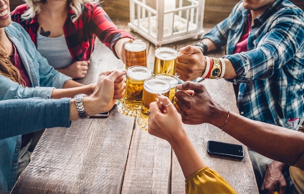 Photo happy diverse young people celebrating together toasting beers