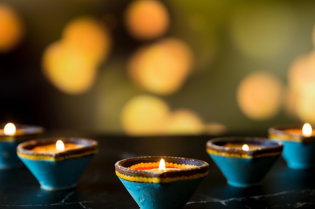 Happy Diwali - Clay Diya lamps lit during Dipavali, Hindu festival of lights celebration. Colorful traditional oil lamp diya on dark background. Copy space for text.