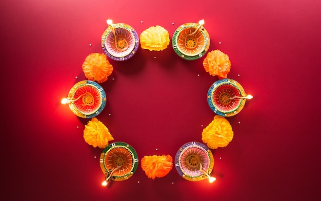 Photo happy diwali clay diya lamps lit during diwali hindu festival of lights celebration colorful traditional oil lamp diya on red background