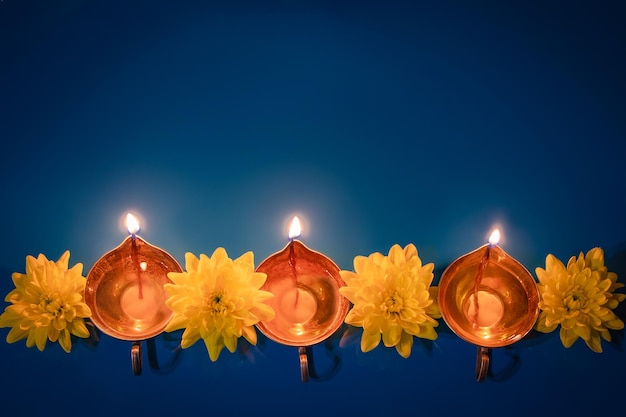 Happy Diwali Diya oil lamps and yellow flowers on blue background Celebrating the traditional Indian holiday of light