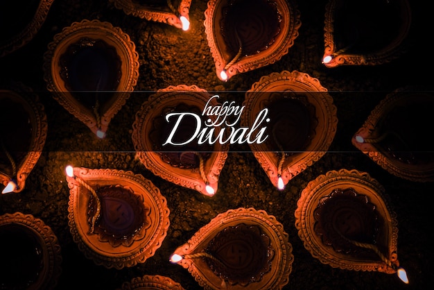 Photo happy diwali greeting card design using beautiful lit diya or clay oil lamps