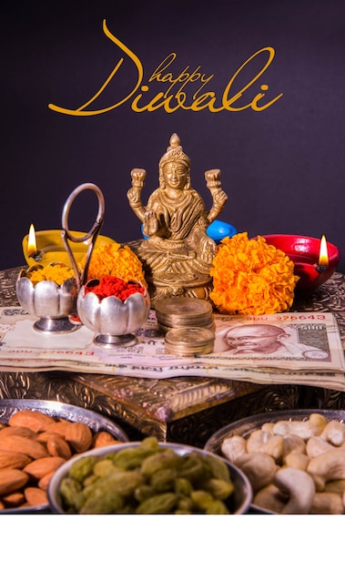 Happy Diwali Greeting card showing oil lamp or diya with fire crackers, Mithai, dry fruits, indian currency notes, marigold flower and statue of Goddess Laxmi or Lakshmi