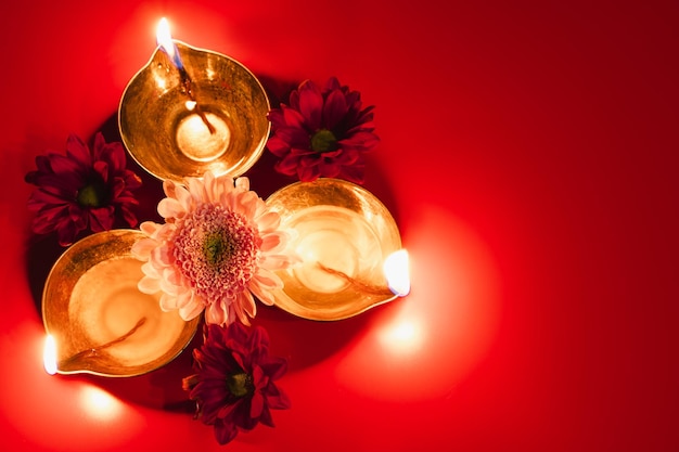 Happy Diwali Traditional Hindu celebration Diya oil lamps and flowers on red background Religious holiday of light