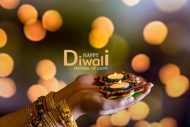Diwali felice - mani della donna con la candela accesa della tenuta dell'henné isolata su fondo scuro. le lampade di clay diya si sono accese durante dipavali, festa indù della celebrazione delle luci. copia spazio per il testo.