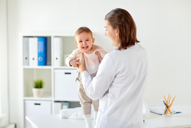 Photo happy doctor or pediatrician holding baby on medical exam at clinic