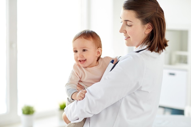 Photo happy doctor or pediatrician holding baby on medical exam at clinic