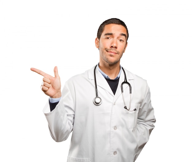 Happy doctor pointing against white background