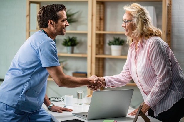 Happy doctor shaking hands with senior woman after medical appointment