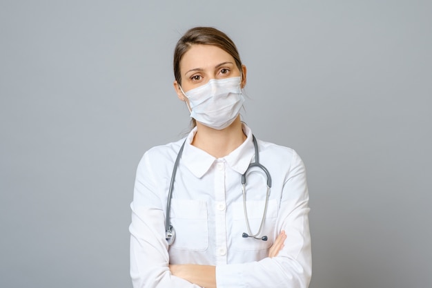 Happy doctor wearing surgical mask isolated on gray