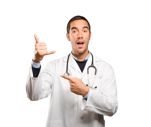 Happy doctor with call gesture against white background