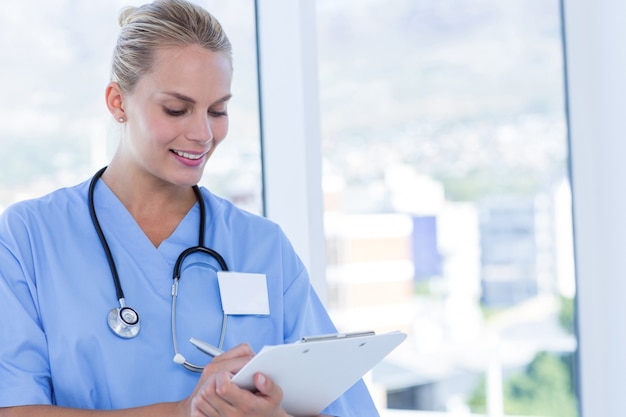 Happy doctor writing on clipboard