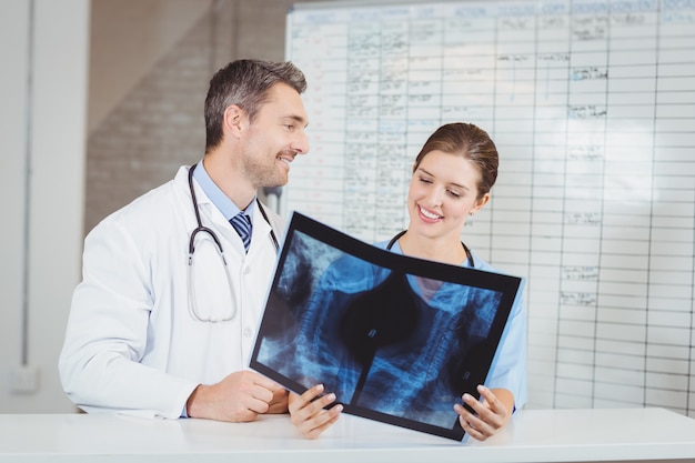 Happy doctors examining X-ray by chart 