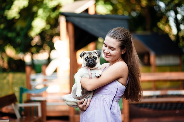 Happy dog and girl The girl is playing with a dog Young woman walking with a pug dog in summer park Portrait of a pug Portrait of a beautiful pug puppy The dog is lying on the ground