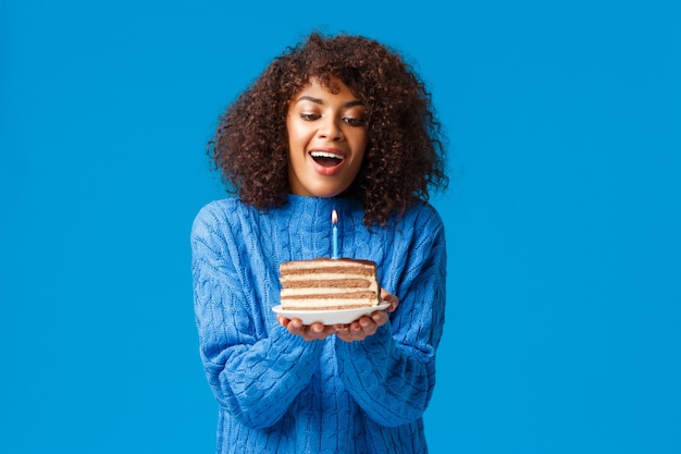 幸せな夢のような希望に満ちた誕生日の女の子が願い事をします。巻き毛のヘアカットと魅力的なアフリカ系アメリカ人の女性