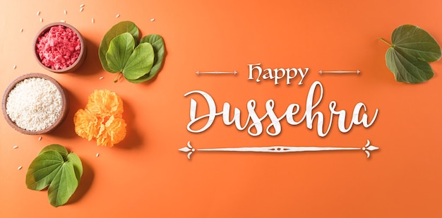 Happy Dussehra Yellow flowers green leaf and rice on orange background