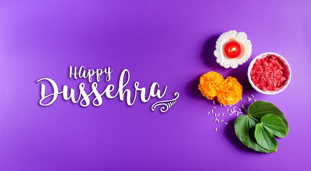 Photo happy dussehra. yellow flowers, green leaf and rice on purple pastel background