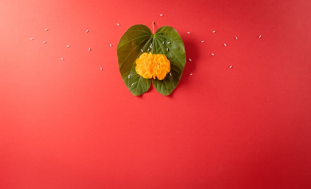 Happy Dussehra Yellow flowers green leaf and rice on red background