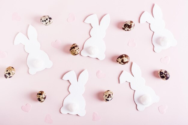 Happy easter background white rabbits quail eggs and hearts on pink top view