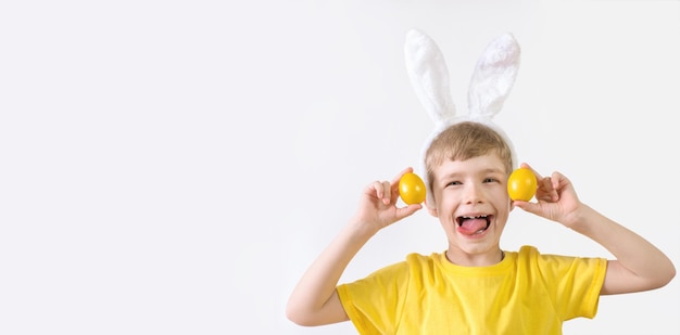 Banner di buona pasqua bambino divertente con una maglietta bianca con orecchie di coniglio e con uova di pasqua colorate