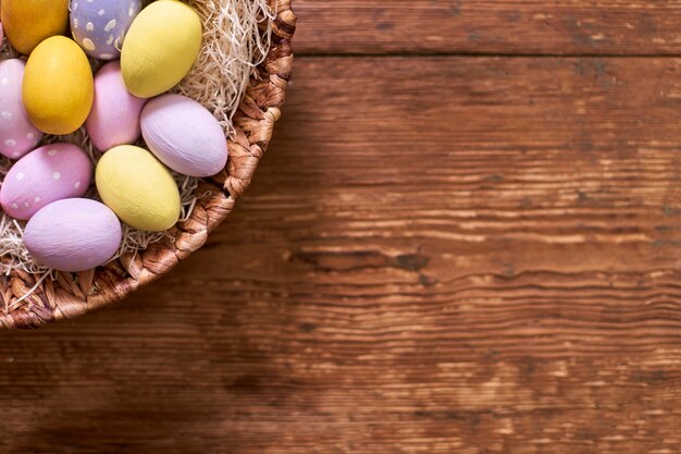 Happy Easter! Basket with Colorful Decorated Eggs Over Rustic Wooden table.