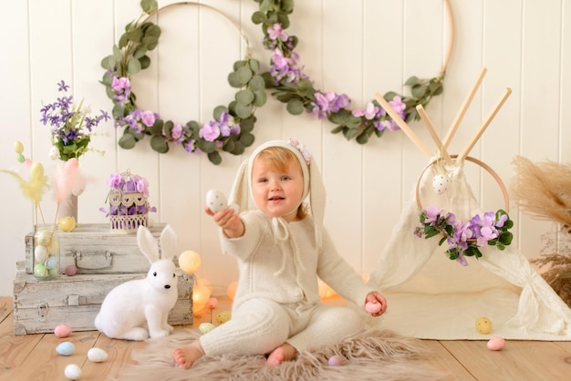 Happy easter bunny girl with colorful eggs sitting in country house and celebrating holiday