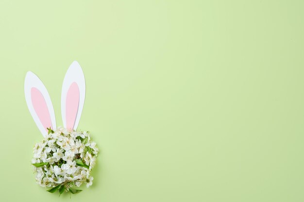 Happy Easter Bunny konijnenoren gemaakt van roze papier en rond boeket van veren, verse kersen- of appelbloesems op groene achtergrond Pasen-wenskaart met kopieerruimte Happy Easter-concept Mock up