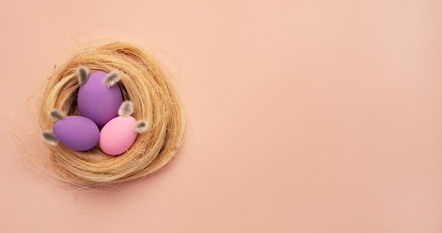 Happy Easter card colored pink easter eggs on a beige nest background from above image