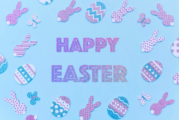 Foto happy easter card glitter decoratieve paarse paaseieren en konijntjes op een blauwe achtergrond sprankelende gradiënttekst happy easter gemaakt in trendy kleuren
