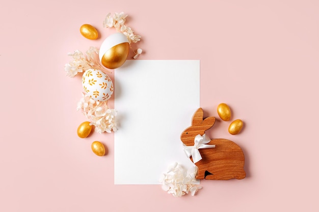 Foto happy easter card mock up scheda vuota con uova d'oro pasquali caramelle e fiori su sfondo rosa pastello concetto di vacanza