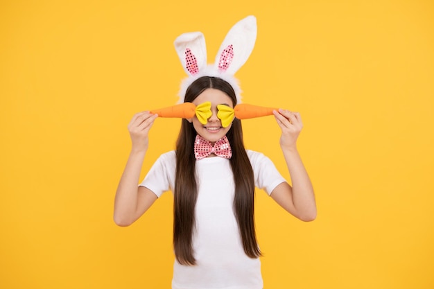 Happy easter child girl in bunny ears and bow tie hold carrot happy easter