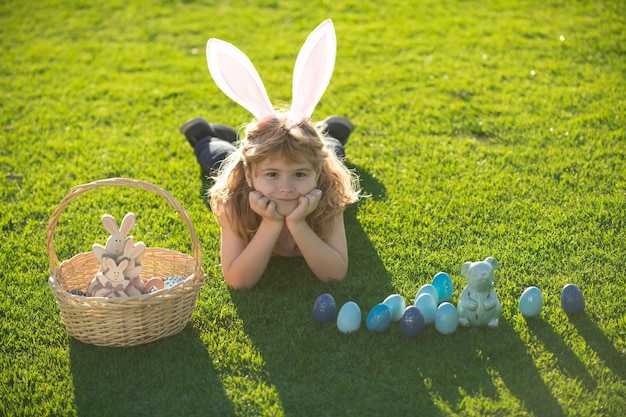 Happy easter child with easter eggs and bunny ears laying on grass happy easter kids face