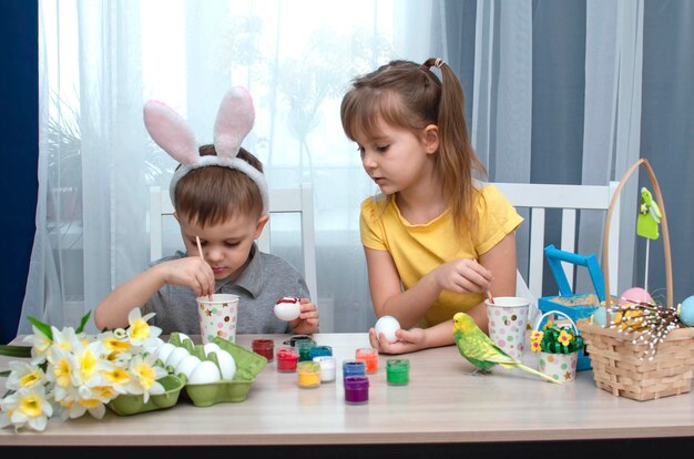 Happy Easter children paint and draw Easter eggs Charming children getting ready for holiday Cute girl and boy decorate Easter eggs