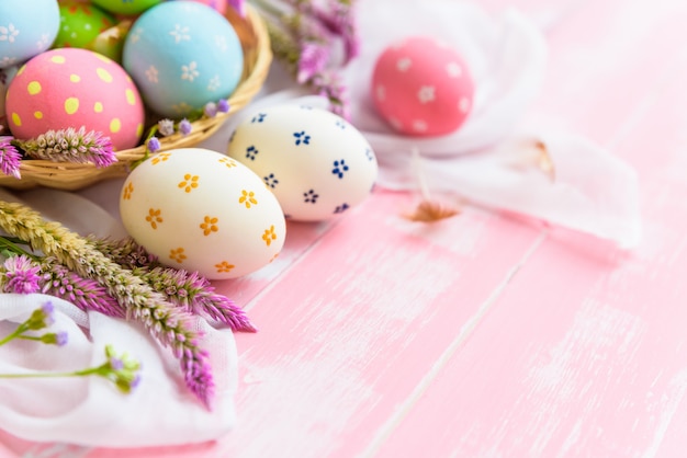 Happy easter! Colorful of Easter eggs in nest with flower on wooden background.