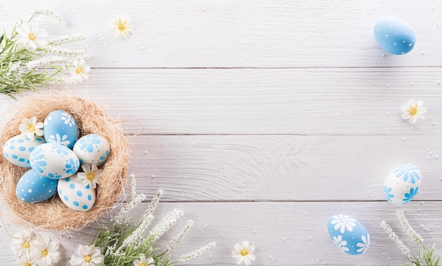 Happy easter colourful Easter eggs and flower on white wooden background