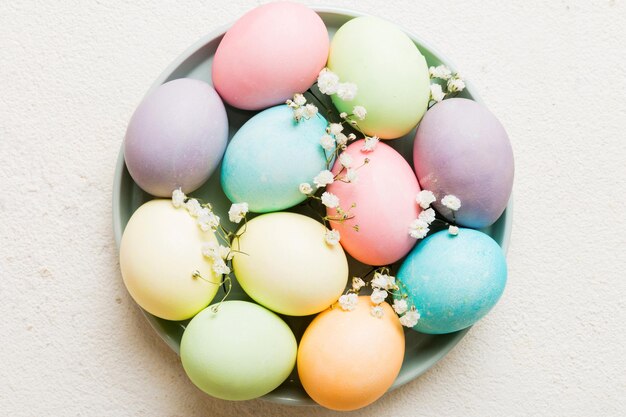 Photo happy easter composition easter eggs in basket on colored table with gypsophila natural dyed colorful eggs background top view with copy space