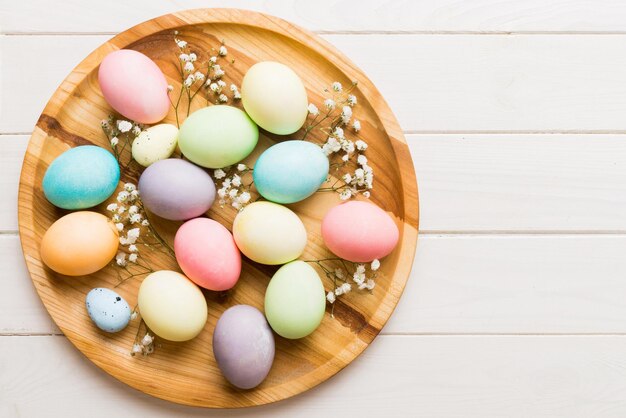 Happy Easter composition Easter eggs in basket on colored table with gypsophila Natural dyed colorful eggs background top view with copy space