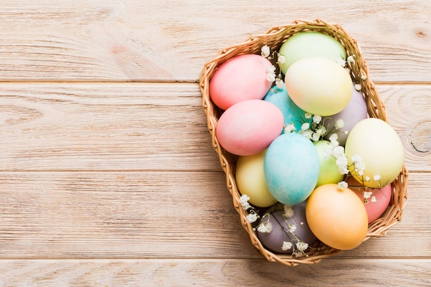 Happy Easter composition Easter eggs in basket on colored table with gypsophila Natural dyed colorful eggs background top view with copy space