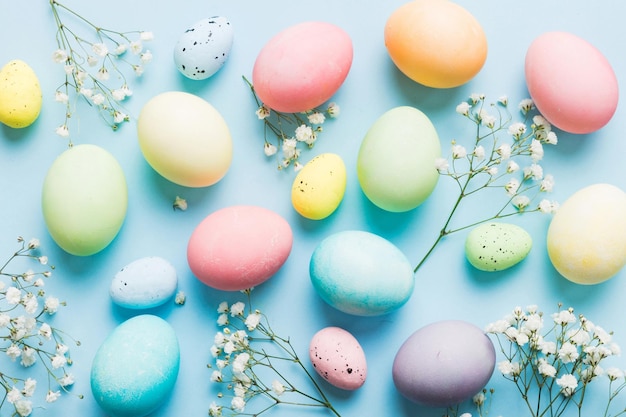 Photo happy easter composition easter eggs on colored table with gypsophila natural dyed colorful eggs background top view with copy space