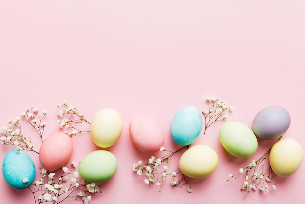 Happy Easter composition Easter eggs on colored table with gypsophila Natural dyed colorful eggs background top view with copy space