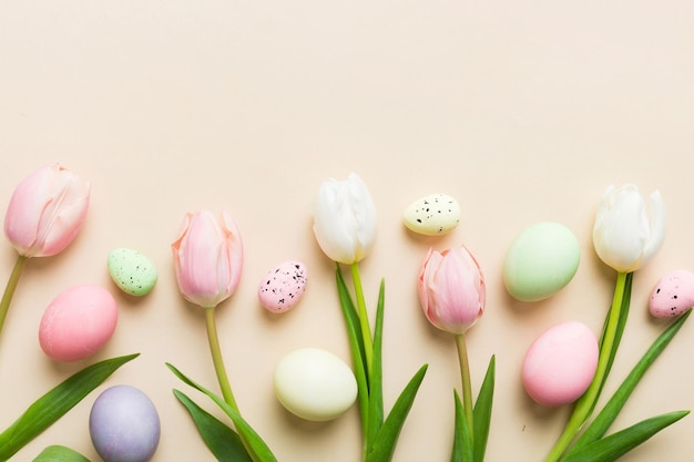 Happy Easter composition Easter eggs on colored table with yellow Tulips Natural dyed colorful eggs background top view with copy space