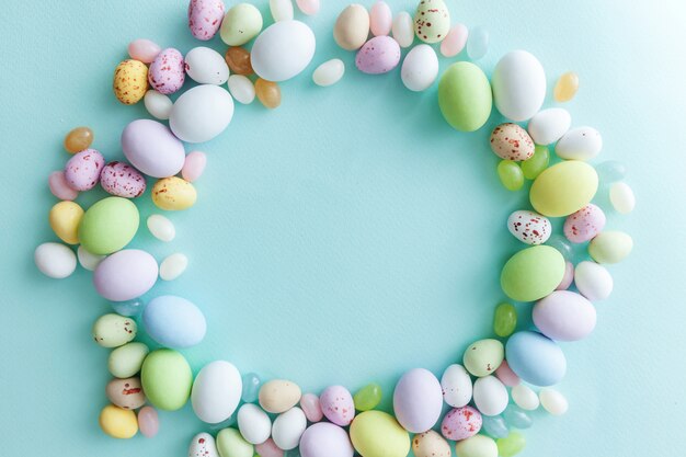 Happy Easter concept. Preparation for holiday. Easter candy chocolate eggs and jellybean sweets isolated on trendy pastel blue background. Simple minimalism flat lay top view copy space.